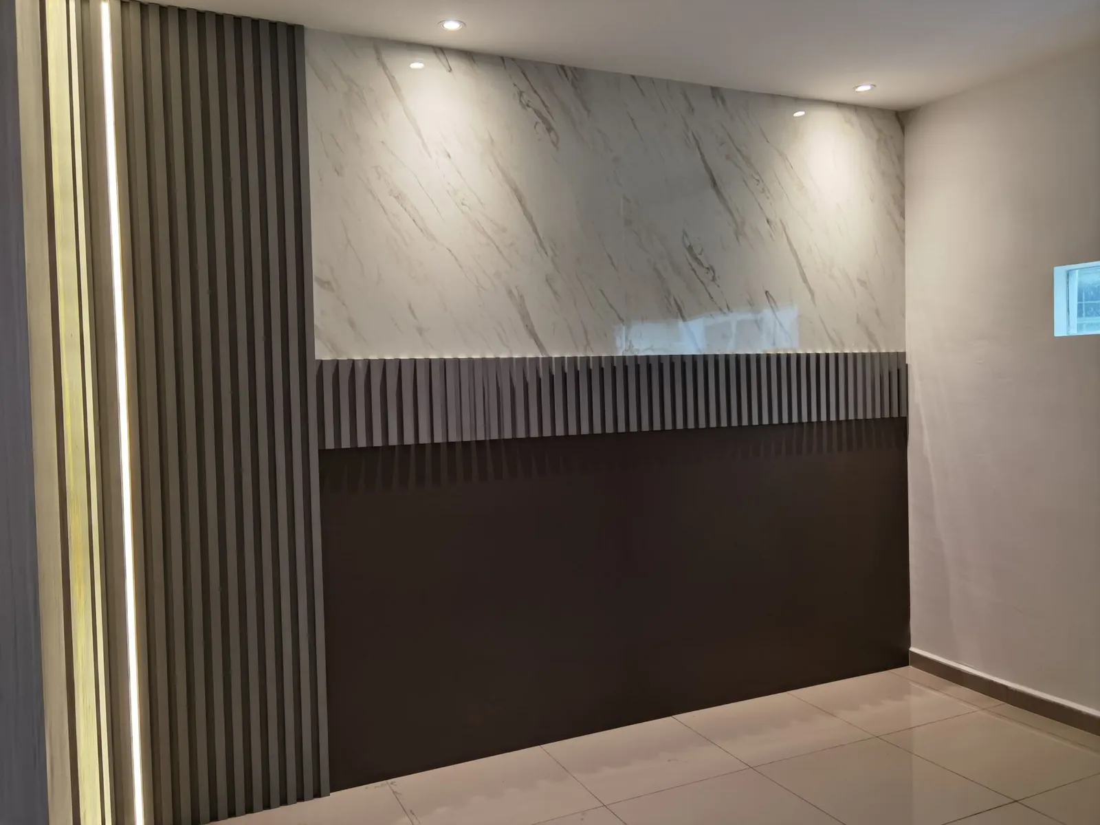 Marble-look feature wall over a dark slatted wainscot at Taman Ara Permai