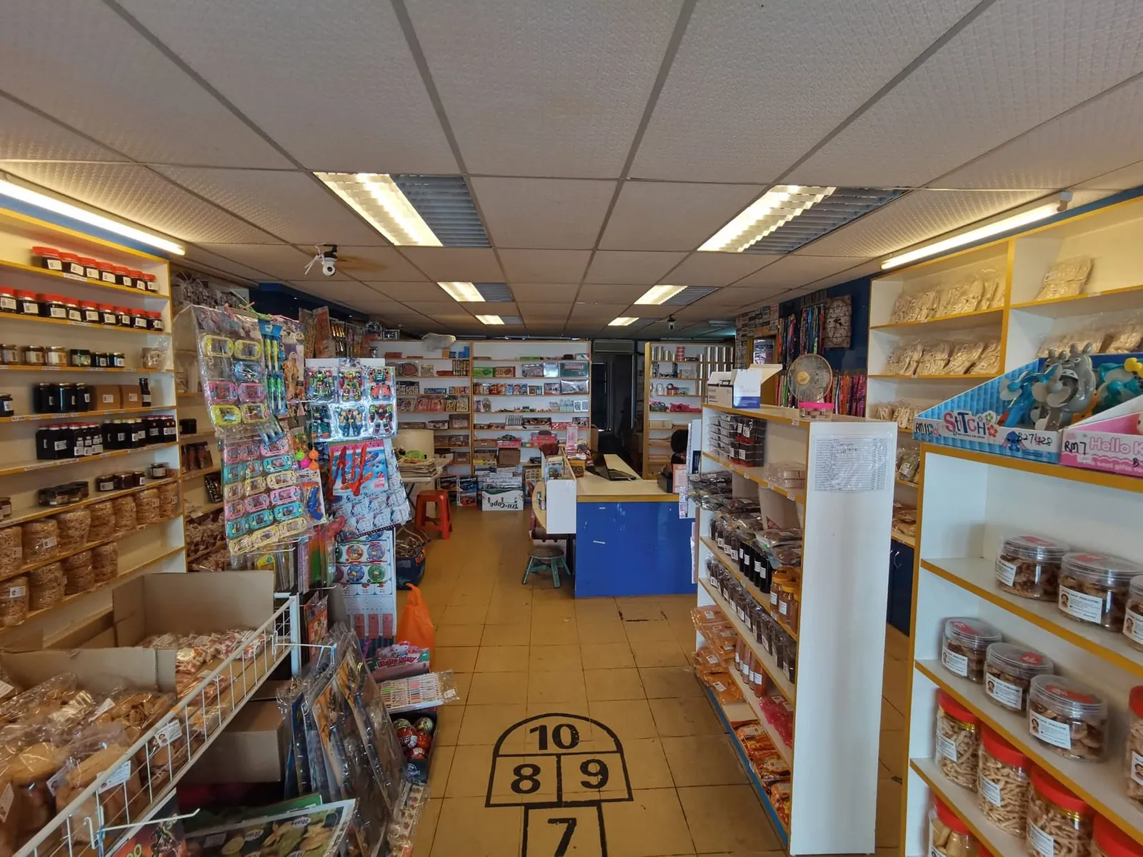 Old Ah Mok Shop aisle packed with goods under a fluorescent grid ceiling