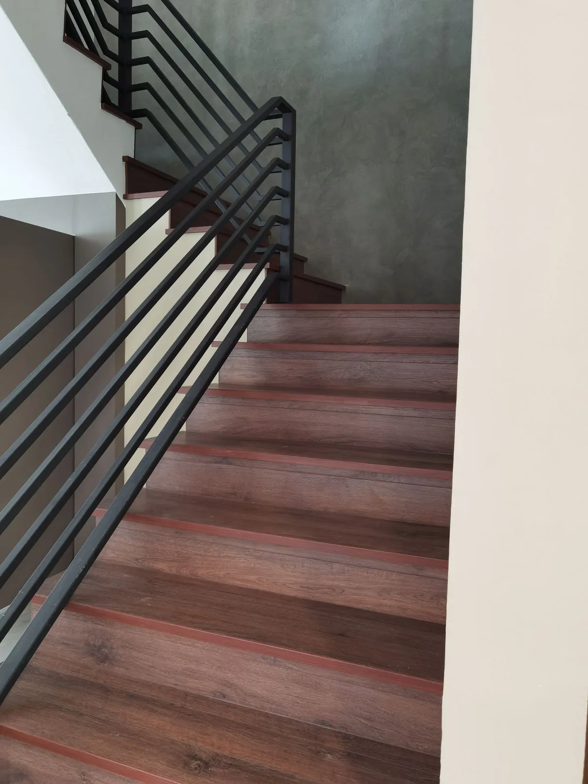 Taman Ara Permai staircase with timber-look treads, black railing and grey feature wall