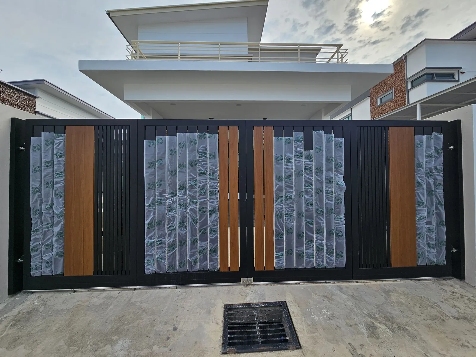 Paya Rumput Perdana 新的黑色木纹板大门，保护膜还没撕