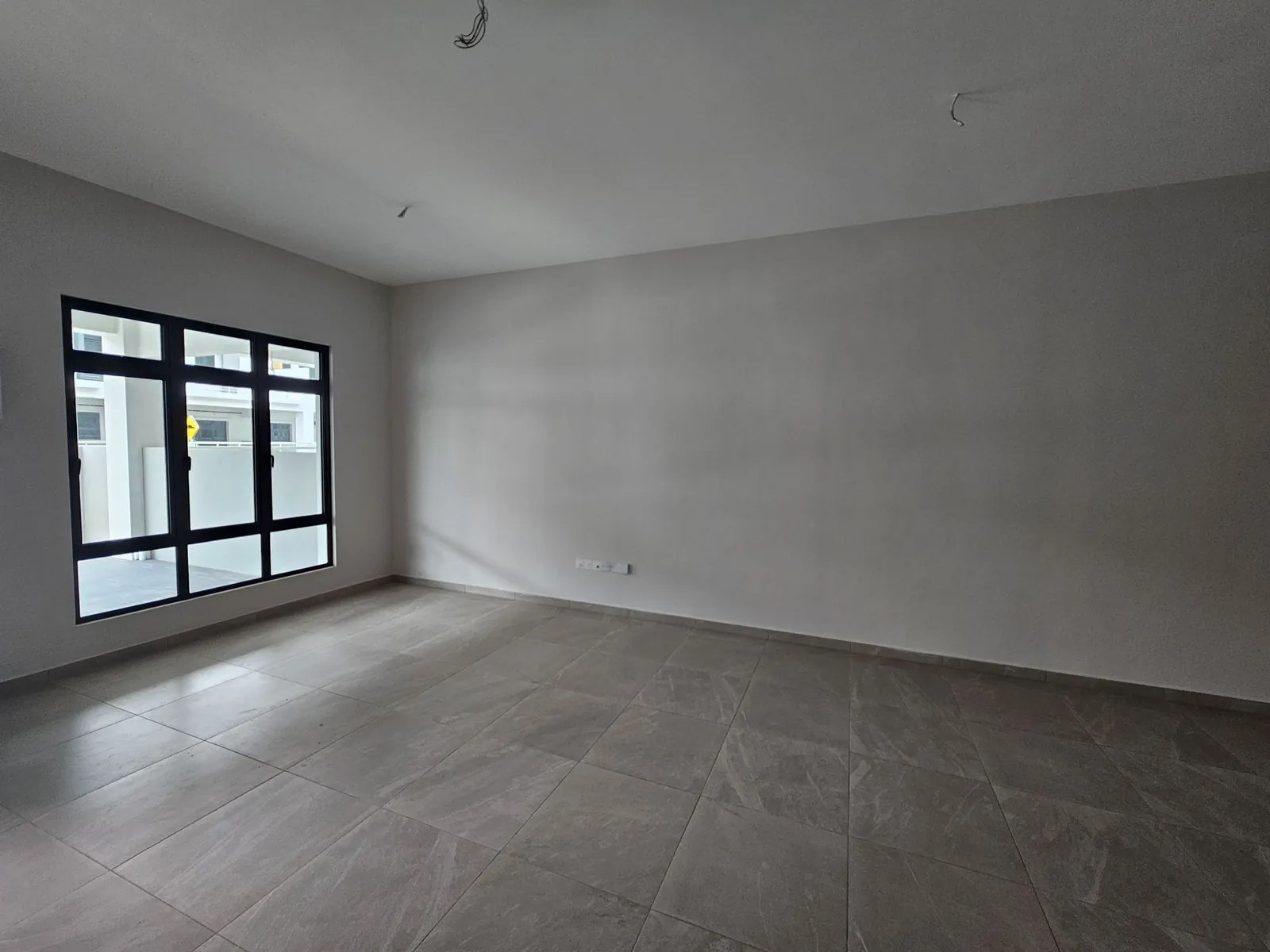Molek Residence 交屋时的空客厅，灰色地砖和黑框窗
