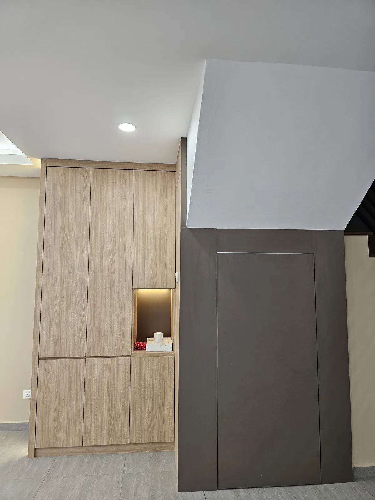 Taman Ara Permai tall wood-grain cabinet with lit niche beside the stairs