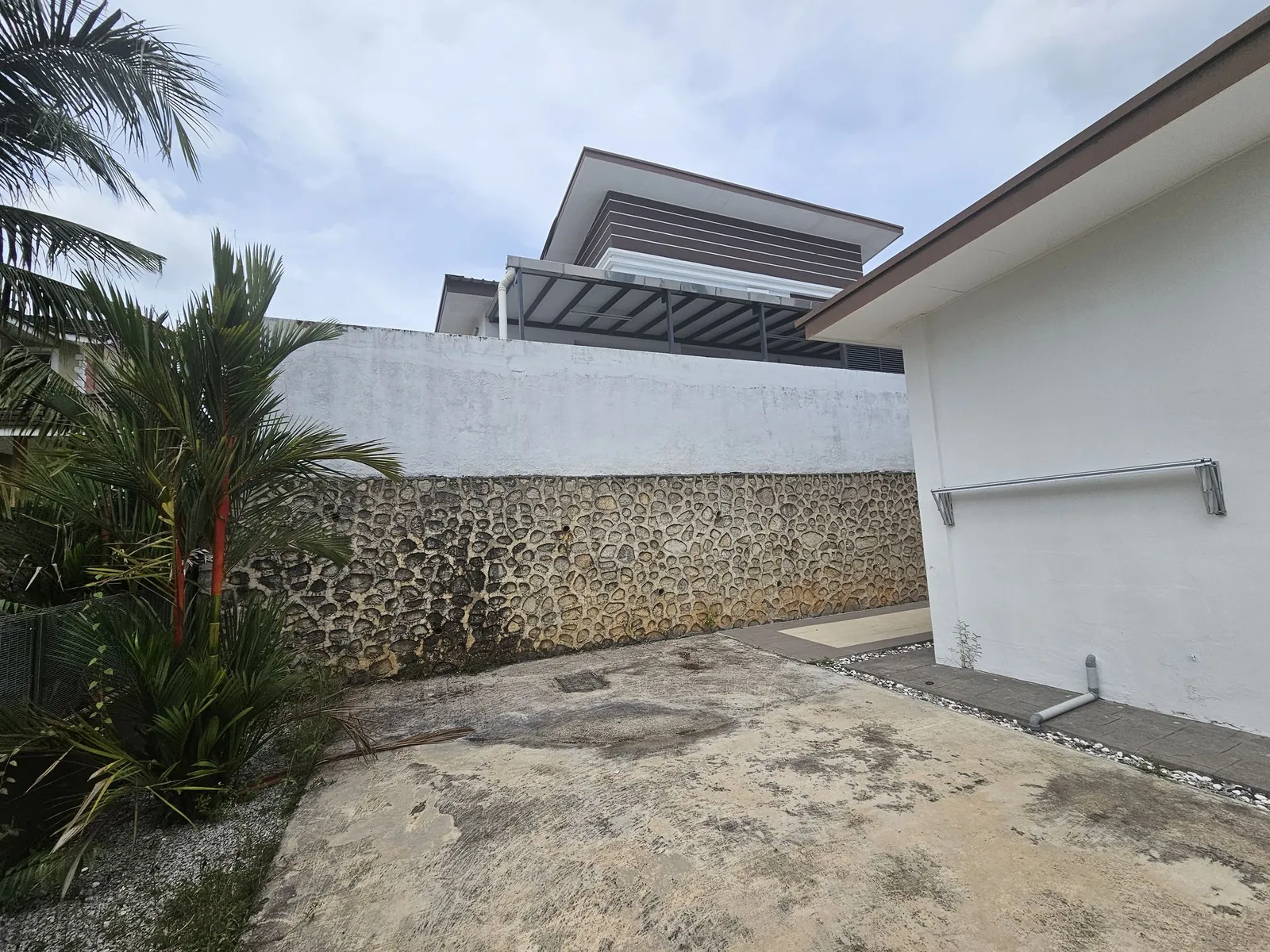 Belia Antarabangsa 动工前的后院：水泥地和石砌挡土墙