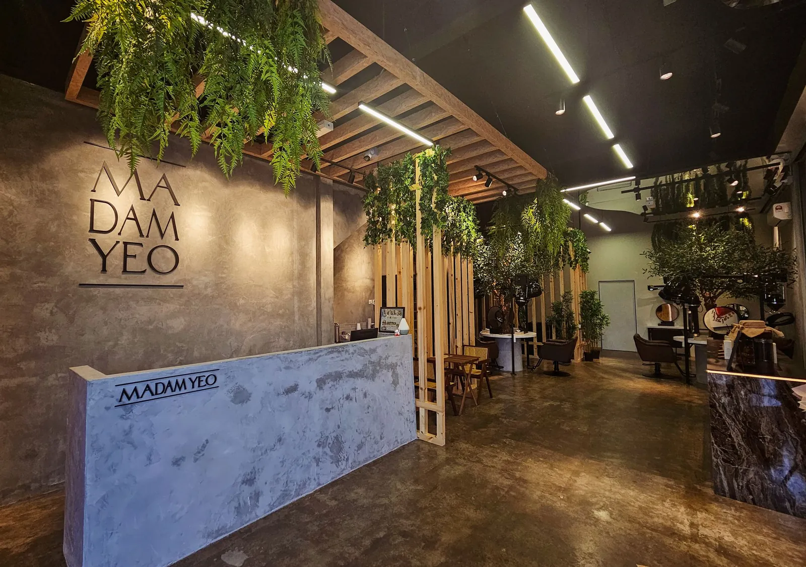 Madam Yeo Hair Care reception with logo wall and hanging greenery