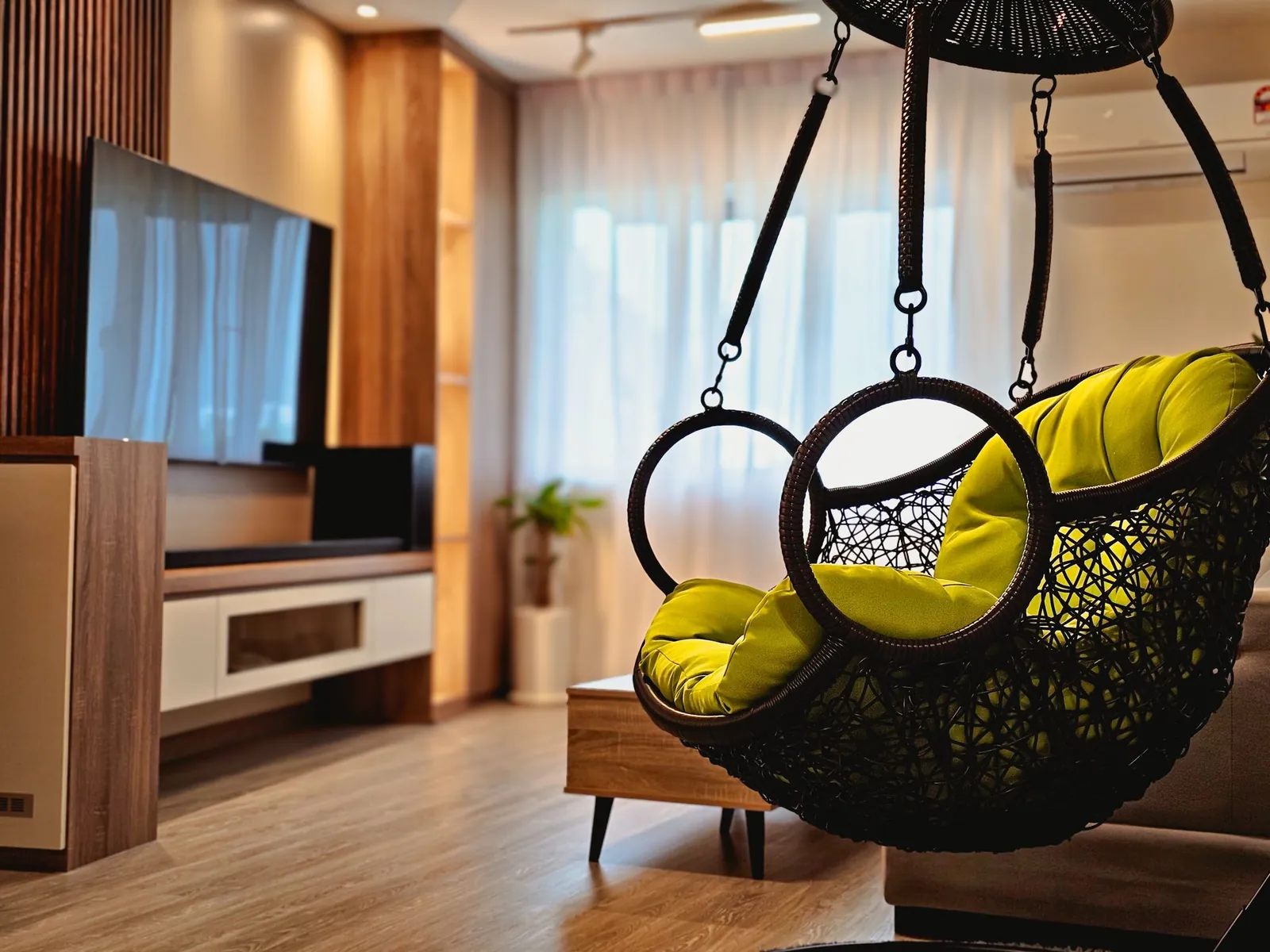 Renovated apartment living room with hanging chair and wood TV wall at Taman Kesidang