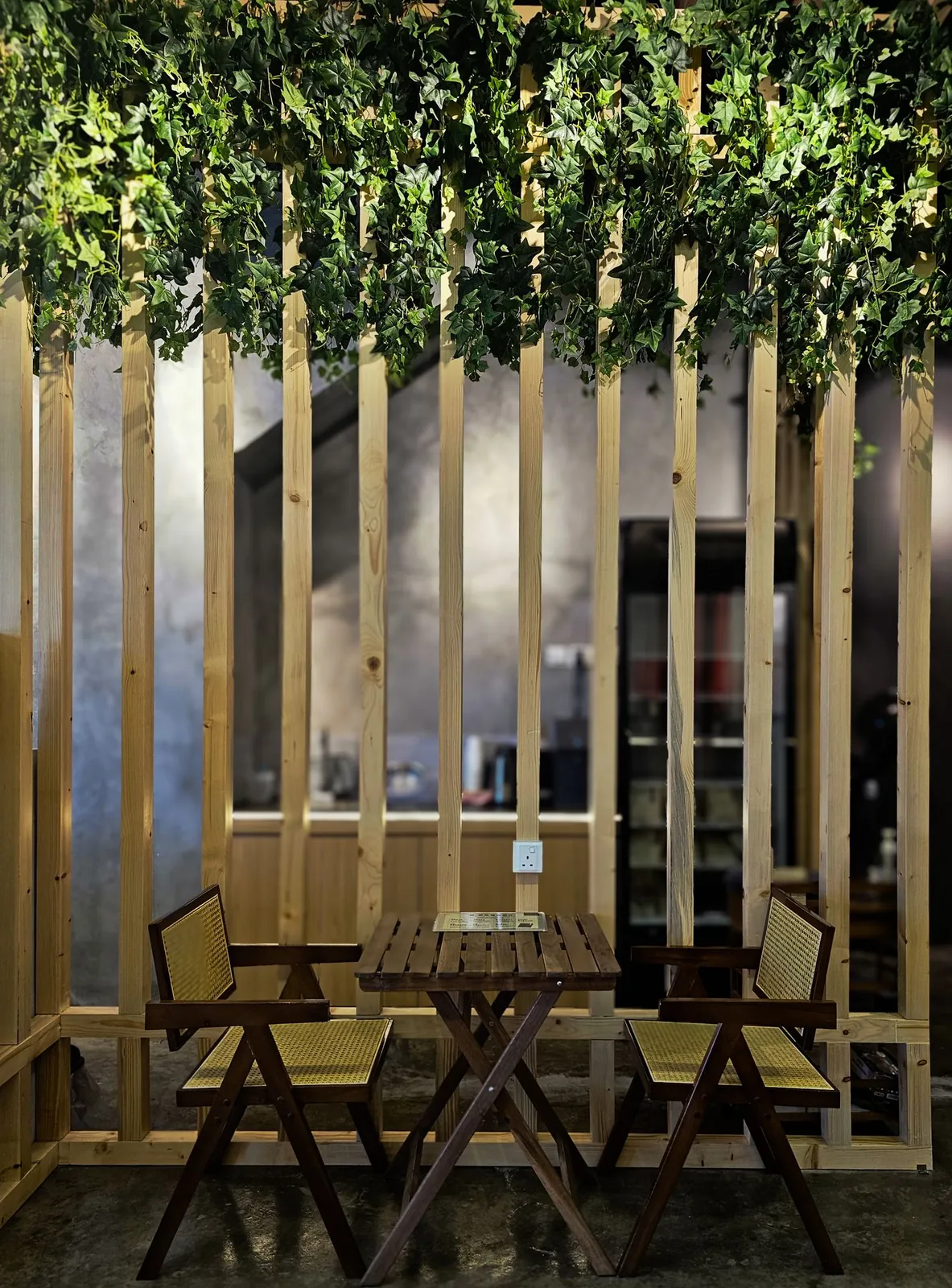 Seating nook with rattan chairs inside a timber slat enclosure at Madam Yeo Hair Care
