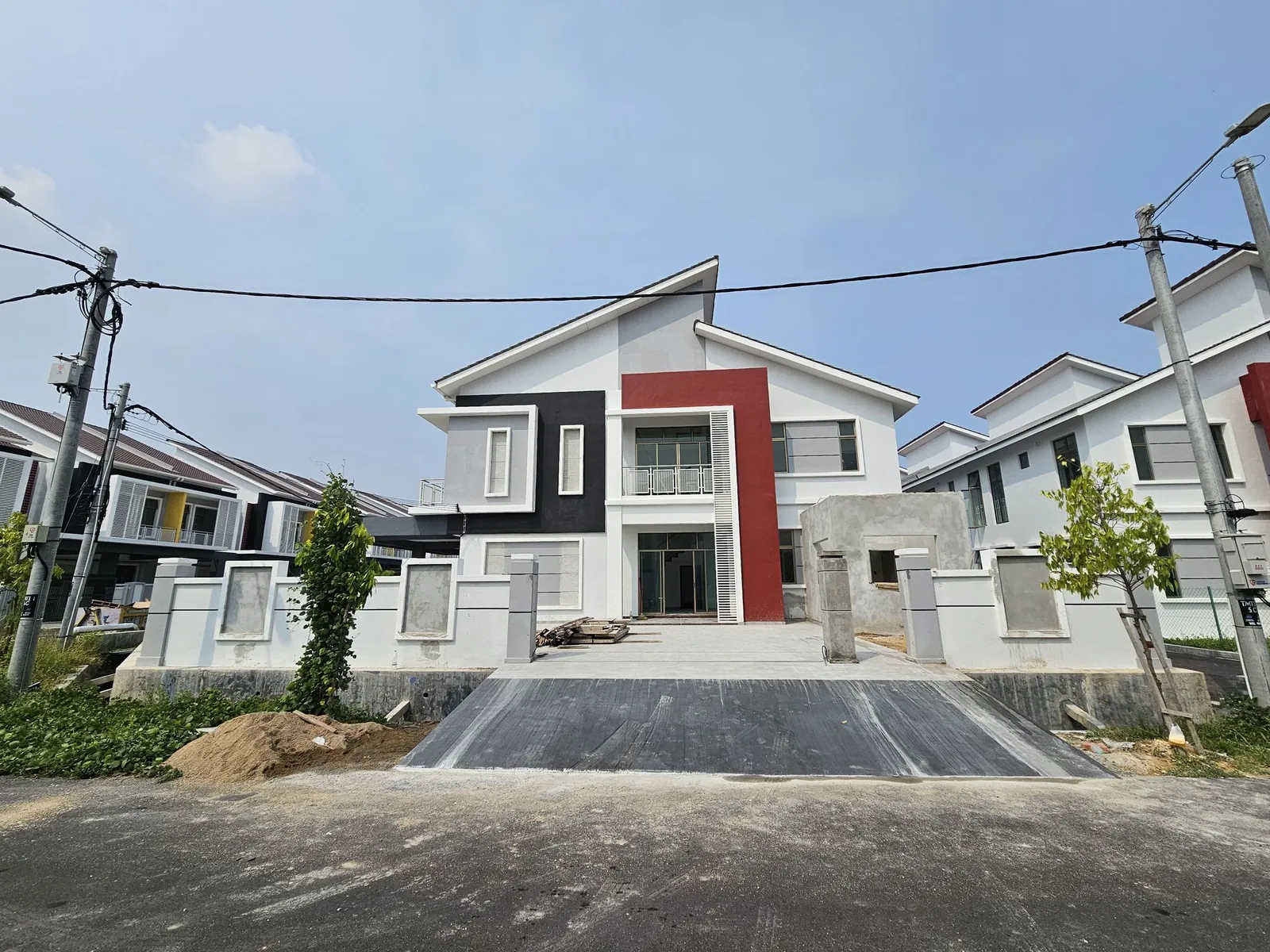 Corner house front with finished dark driveway and extension under construction at Tehel Indah