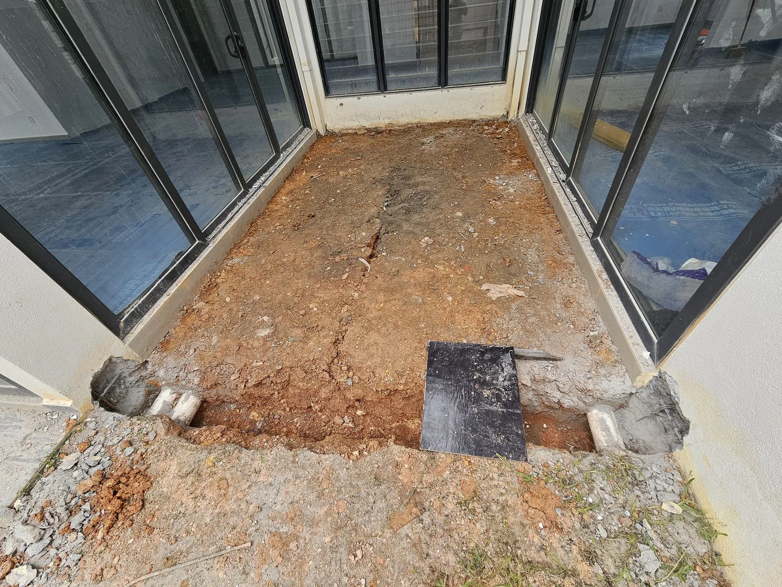 Dug-up soil in the light-well between glass doors at a Country Villa house
