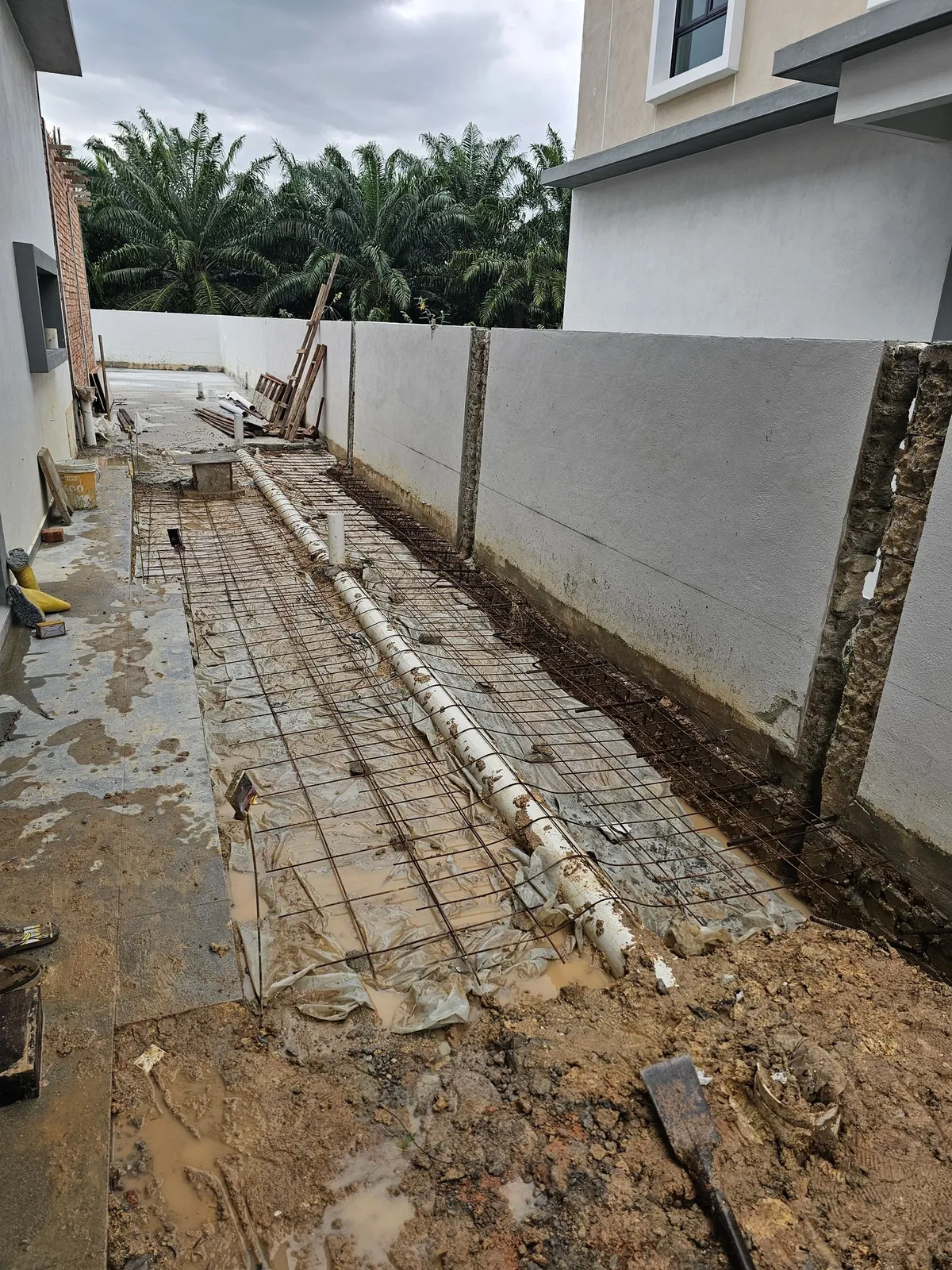 Jasin Parkland side yard with reinforcement mesh and a drain pipe along the wall