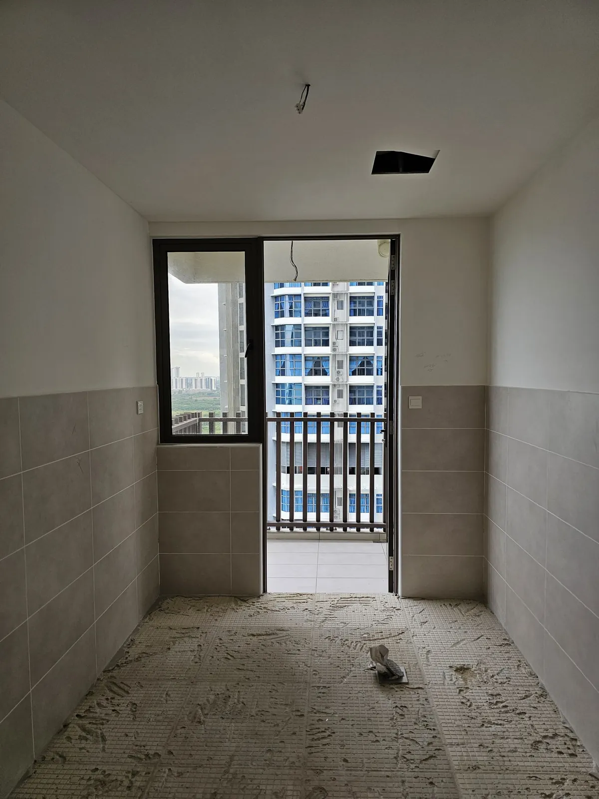 Bali Residence galley kitchen before work, grey wall tiles and bare floor
