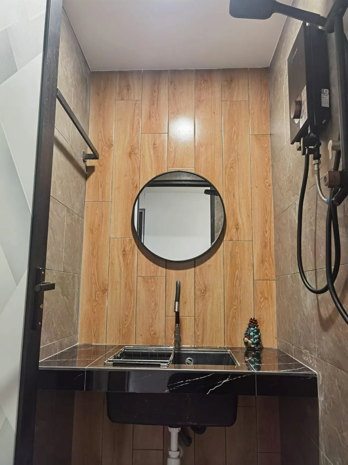 Basin area with round black mirror and wood-look tiles at Ah Mok Shop