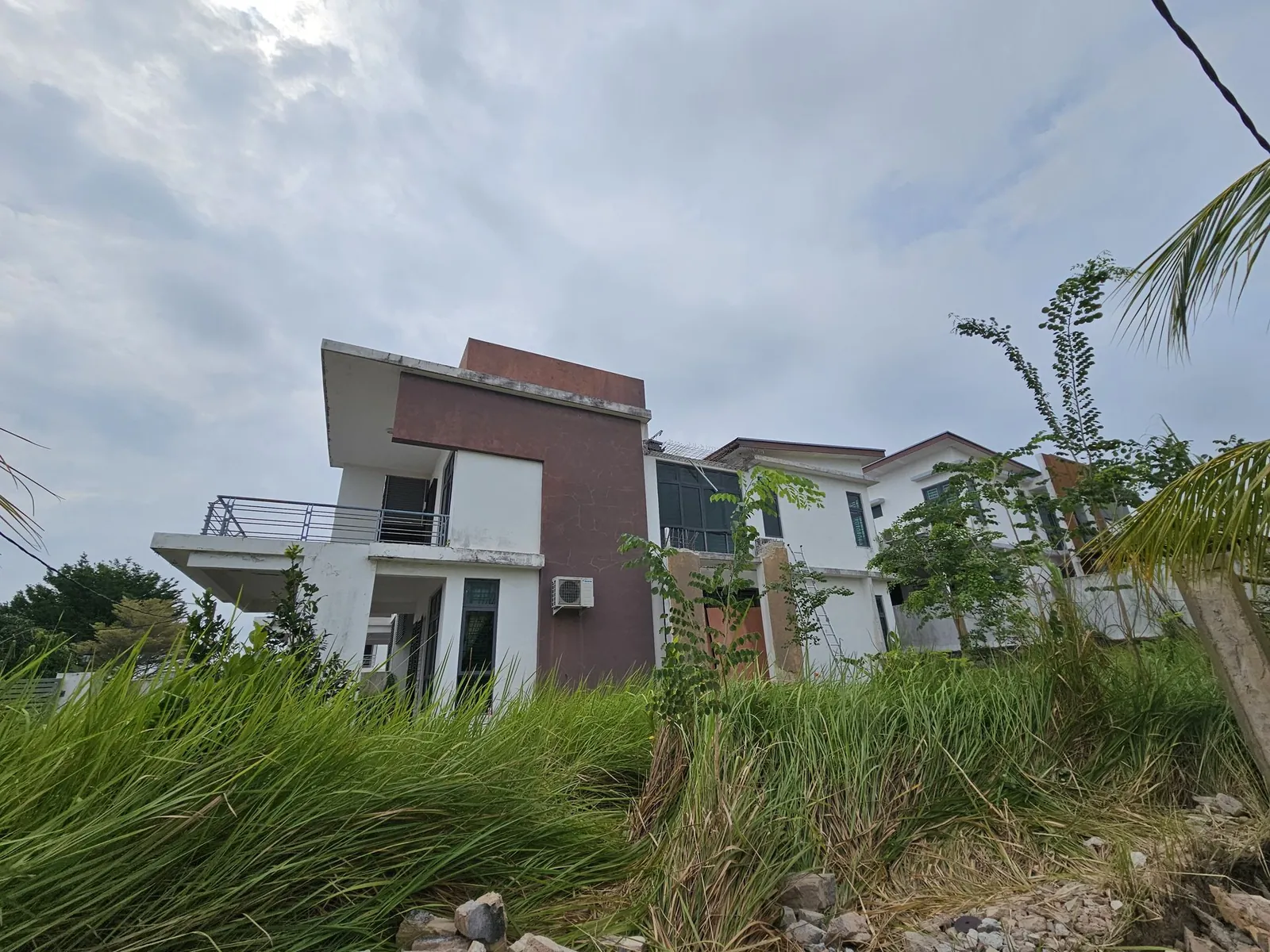 Vista Kirana 施工前的屋子侧面，前面是高高的杂草